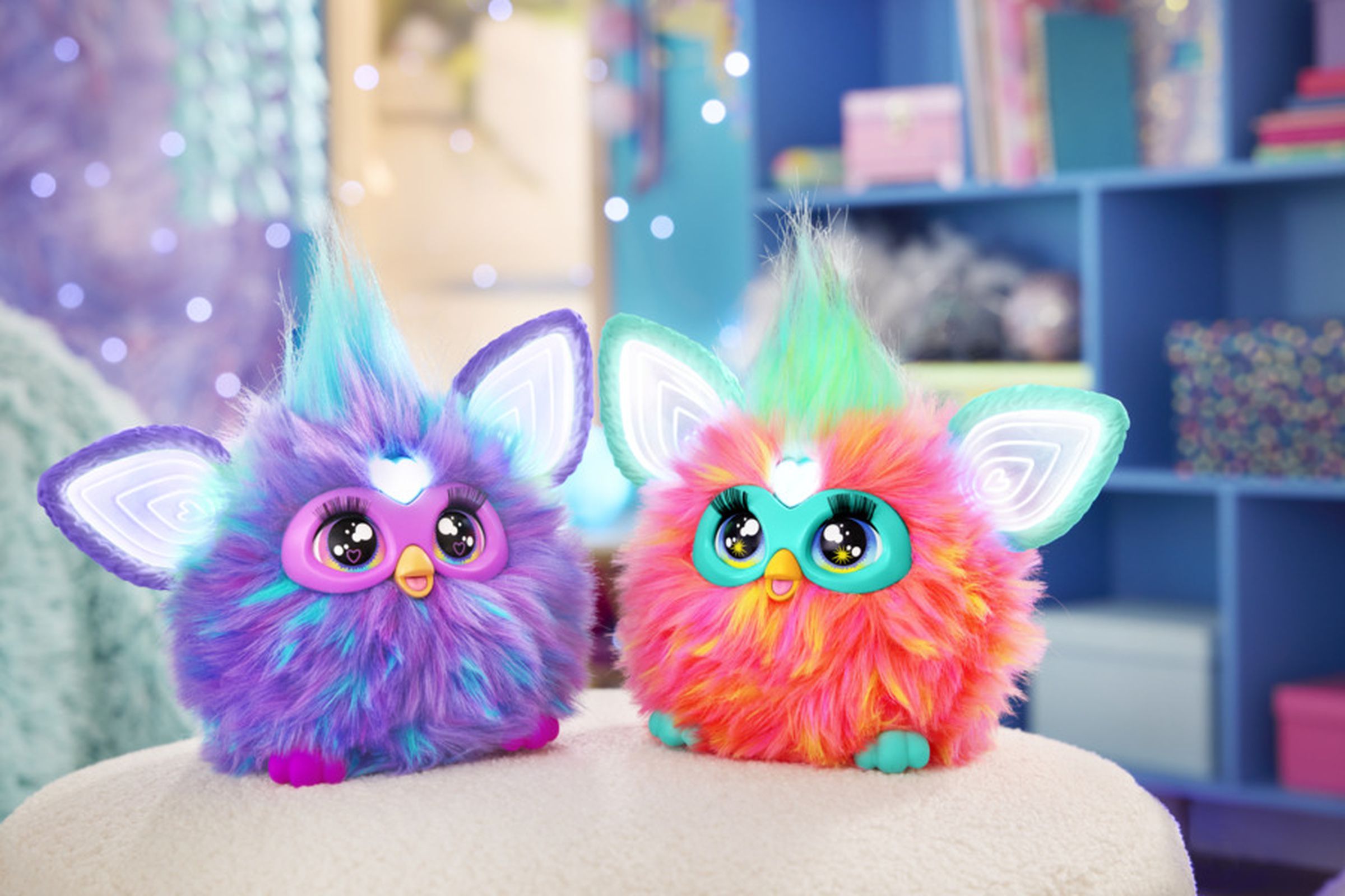 Two Furbys sit next to one another.