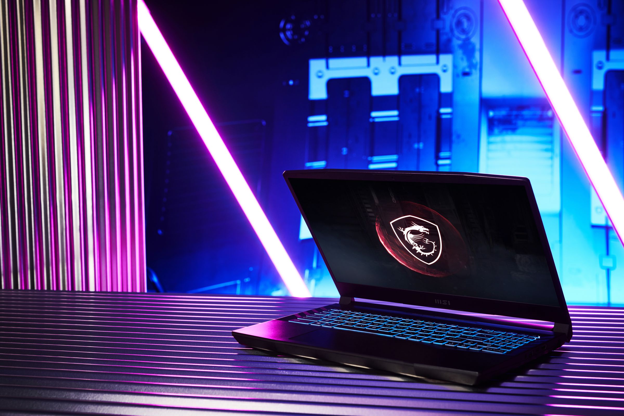 The MSI GL66 Pulse half open on a table, with black and purple lights in the background. The screen displays the MSI dragon-shield logo on a black background.