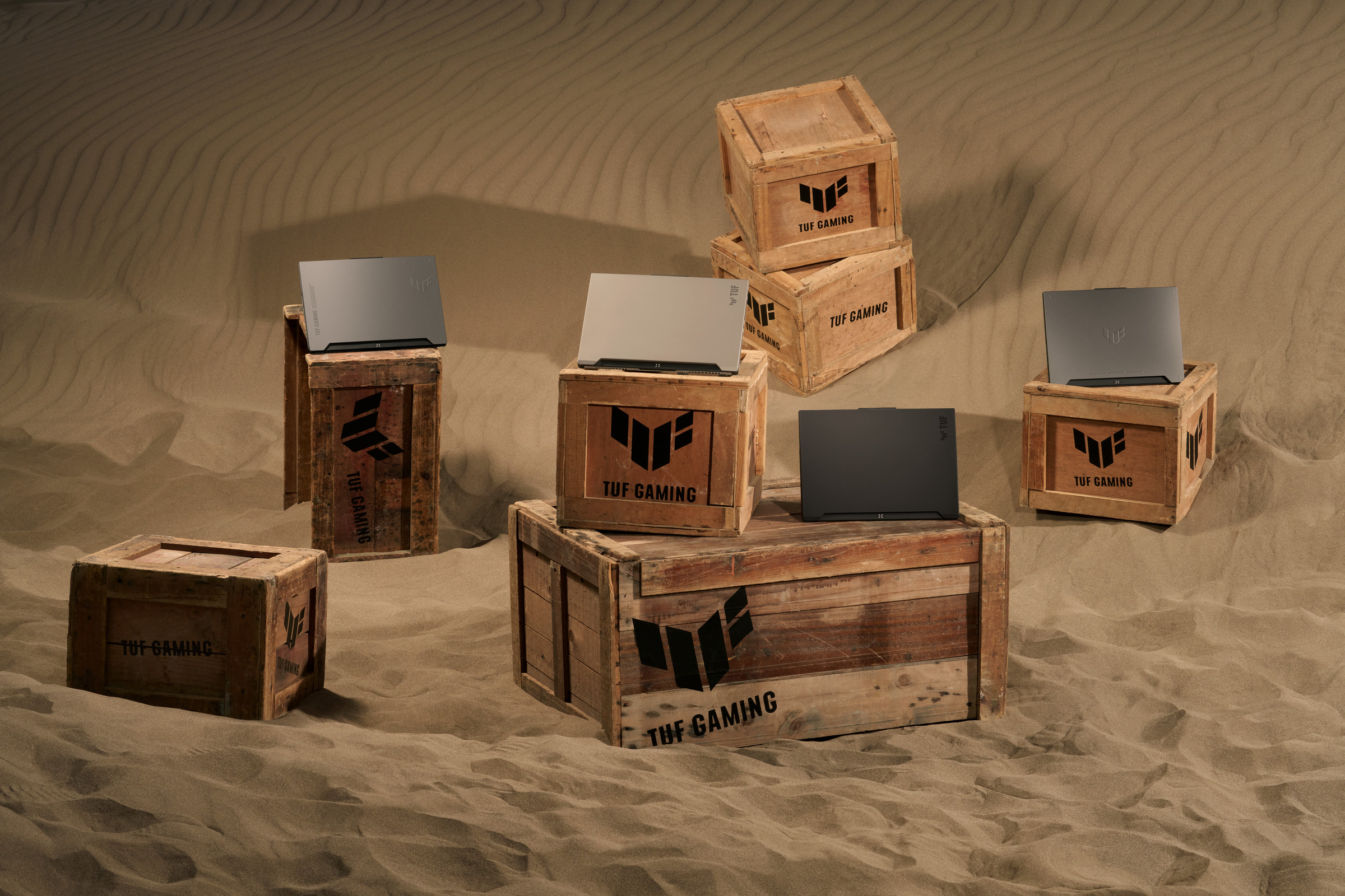 Four TUF Gaming laptops facing away from the camera arranged atop a bunch of crates.