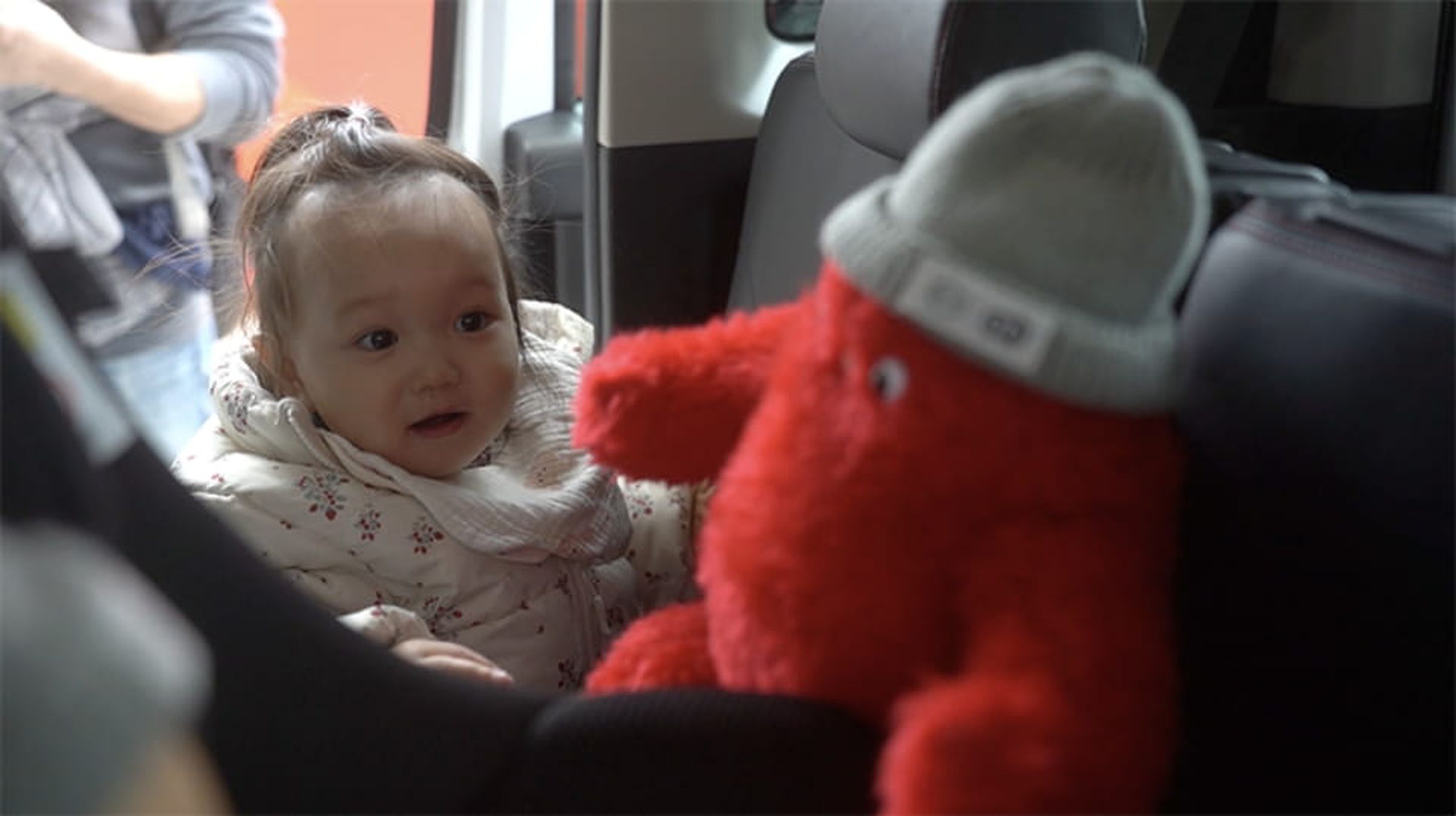 A baby looking at Iruyo in a car.