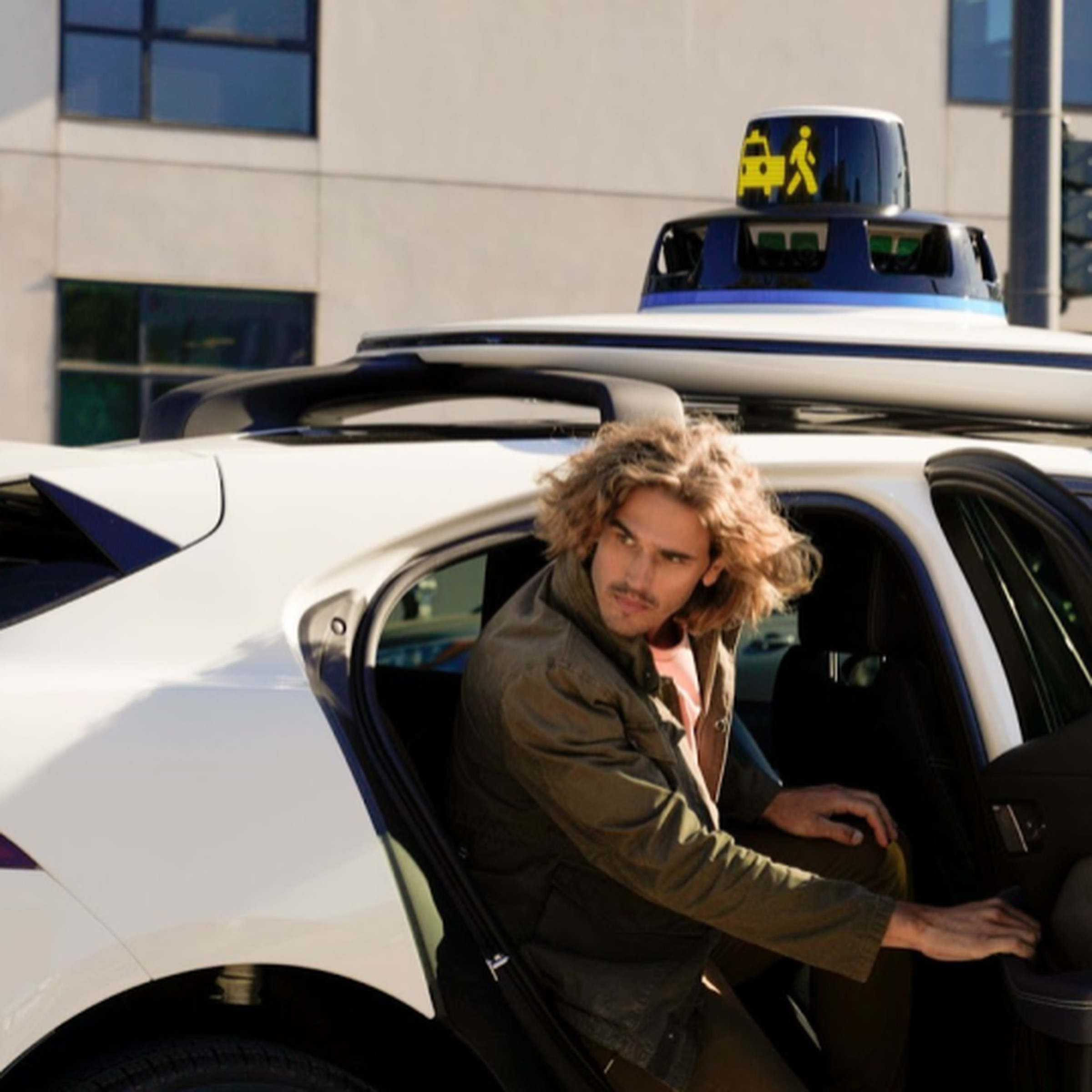 Person exiting a driverless Waymo vehicle with visual cues on roof dome.