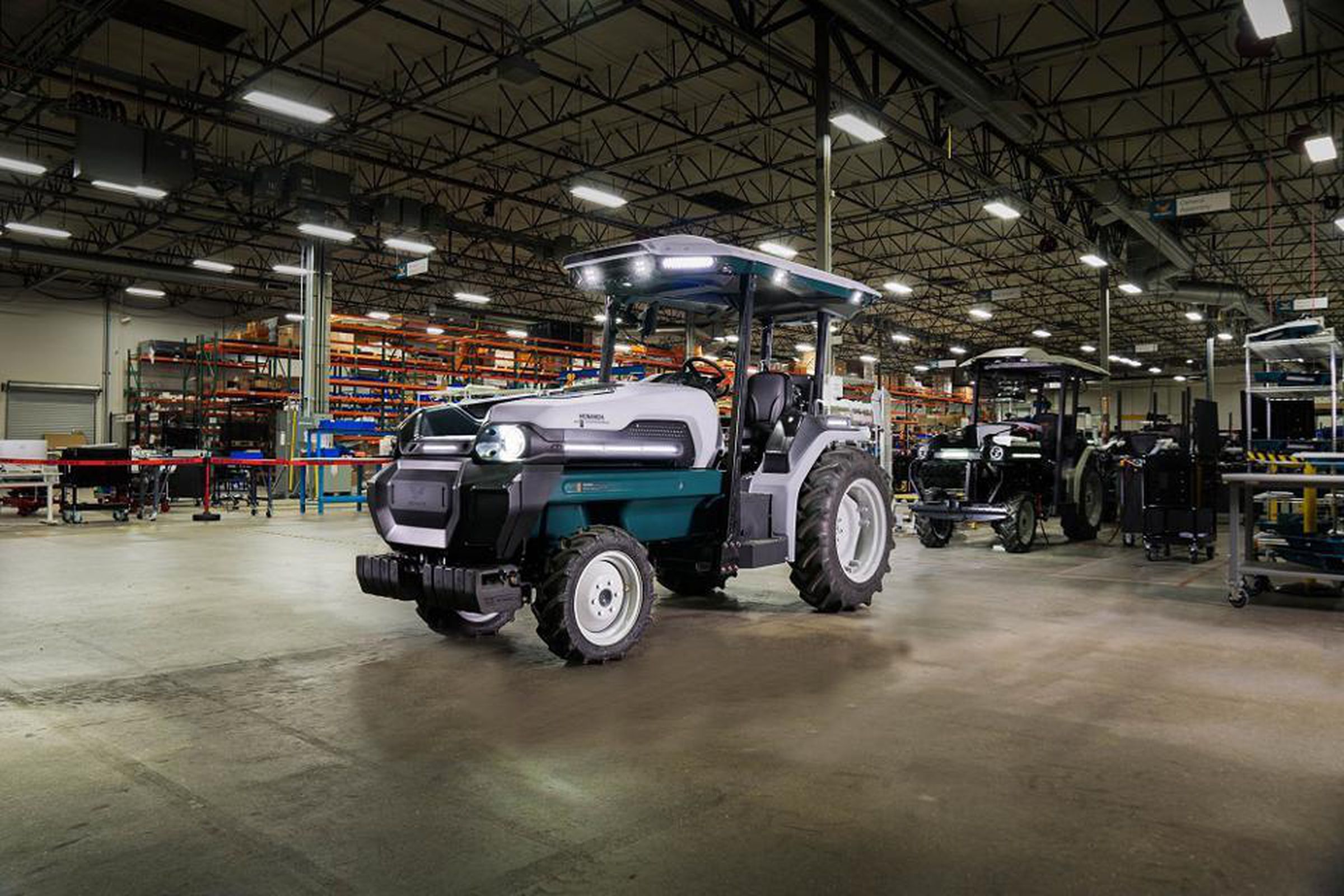 The new MK-V smart tractor is parked in the middle of a warehouse factory with a concrete floor.