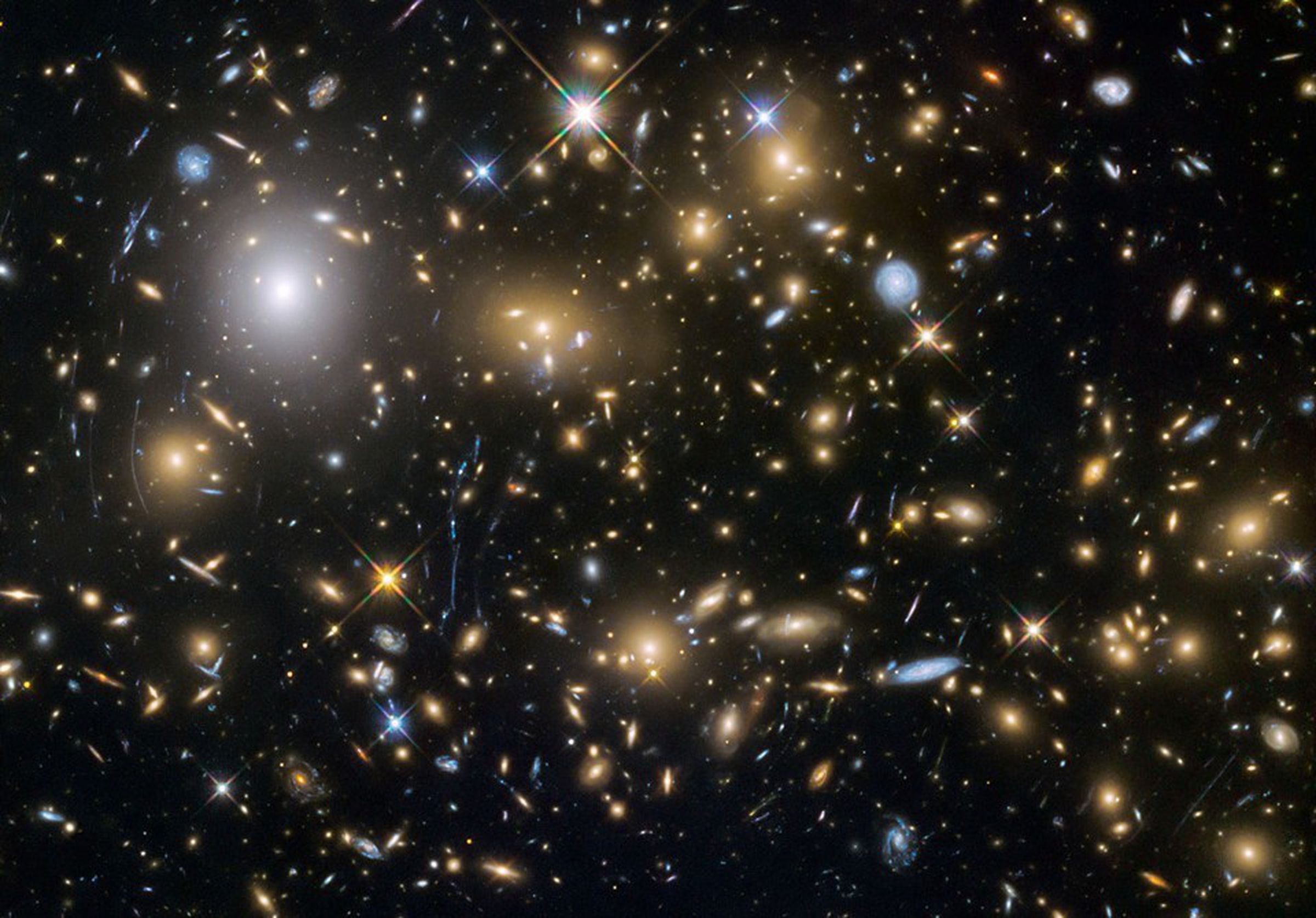 A shot of multiple galaxies taken by the Hubble space telescope. The curved smears of light are gravitational lenses.