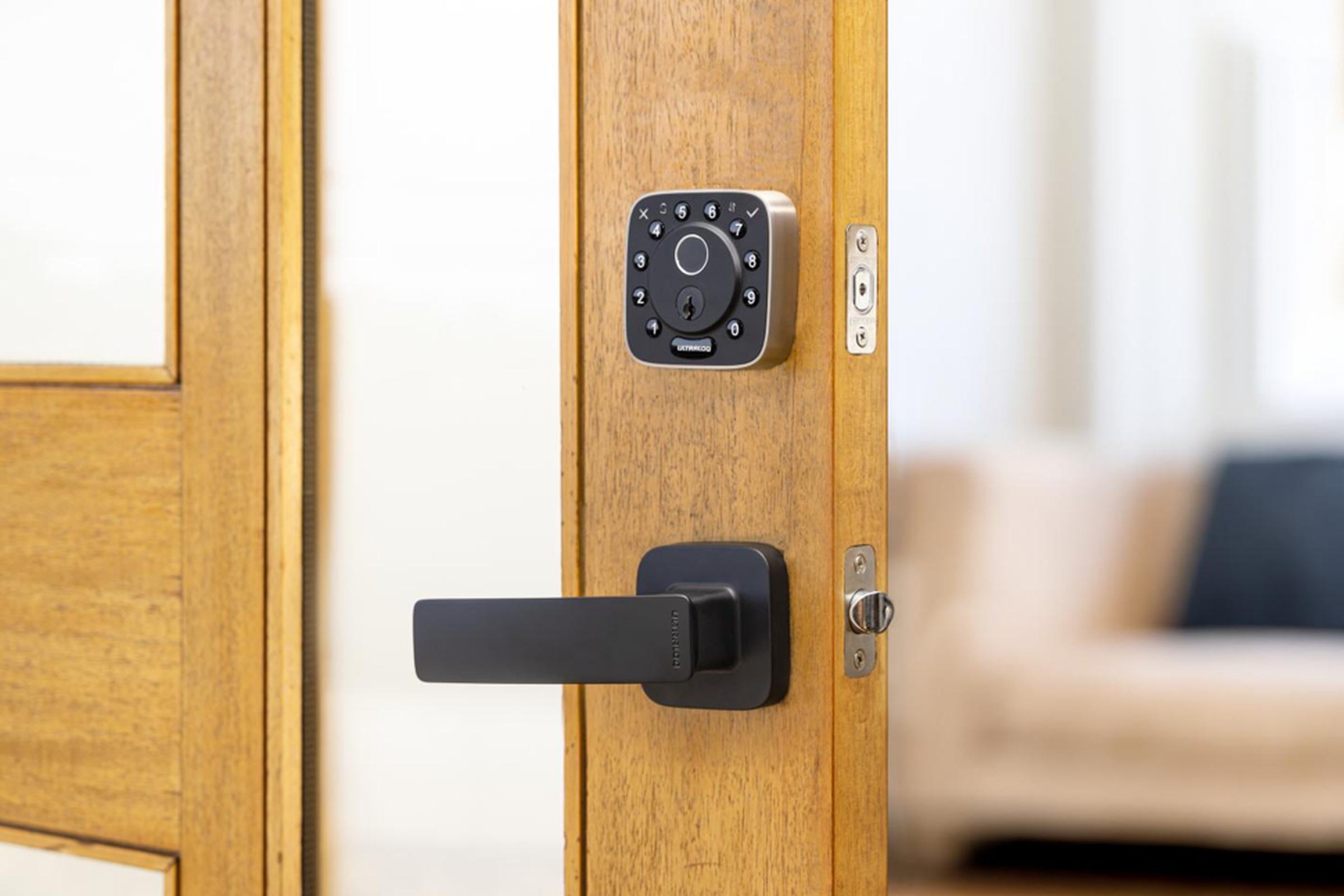 A black smart lock on a wooden door.