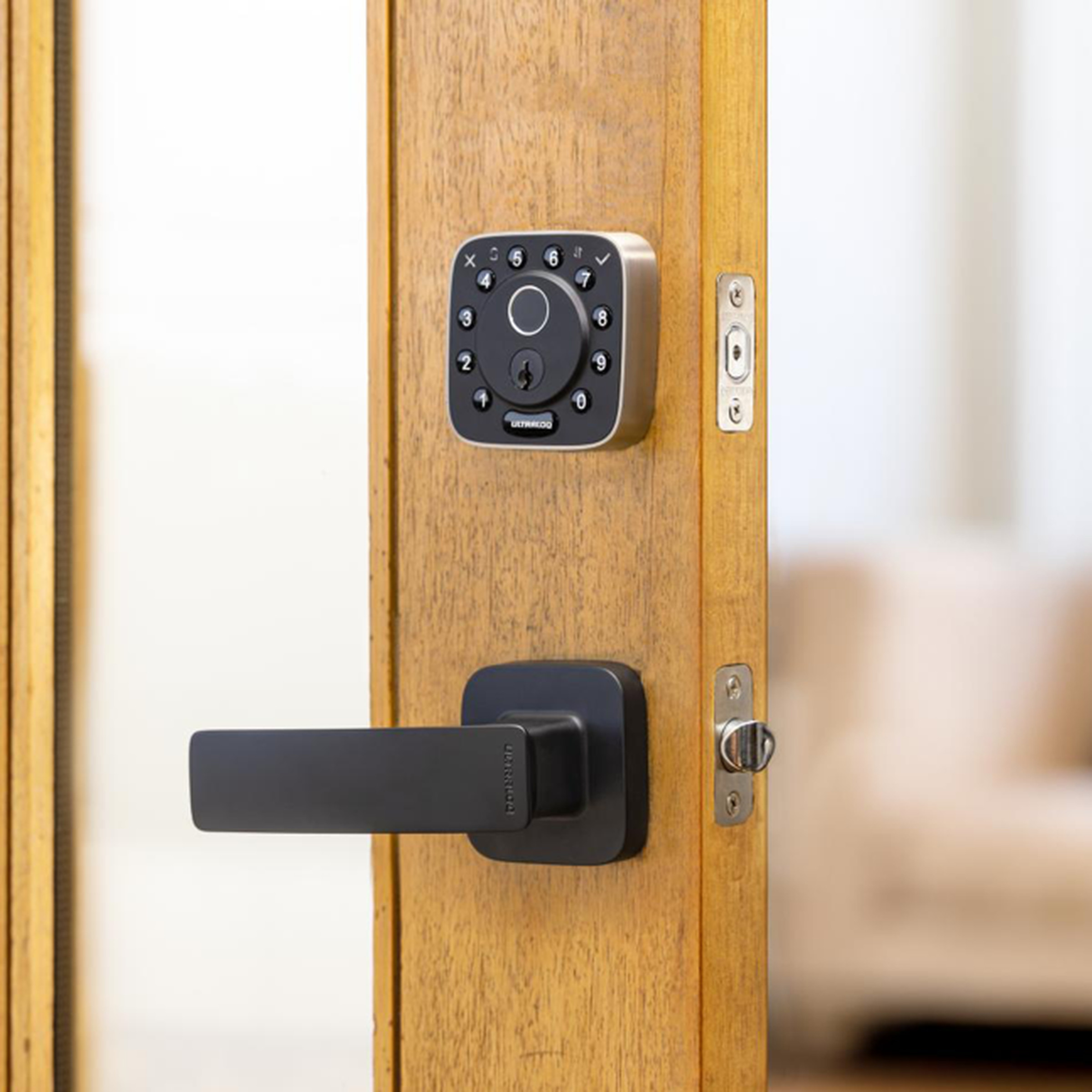 A black smart lock on a wooden door.