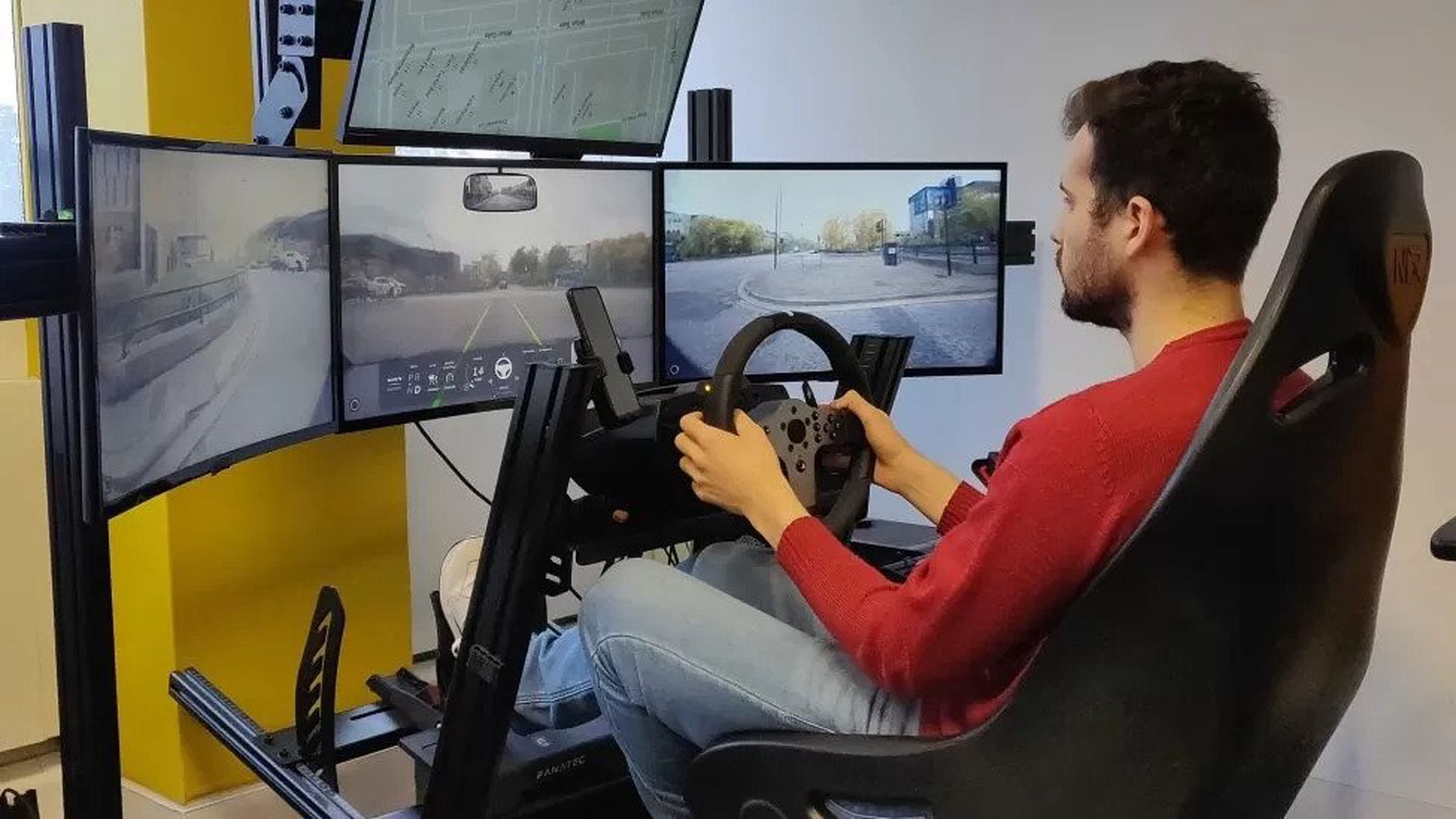 A man sat in a driving simulation setup remotely piloting a Fetch rental car.