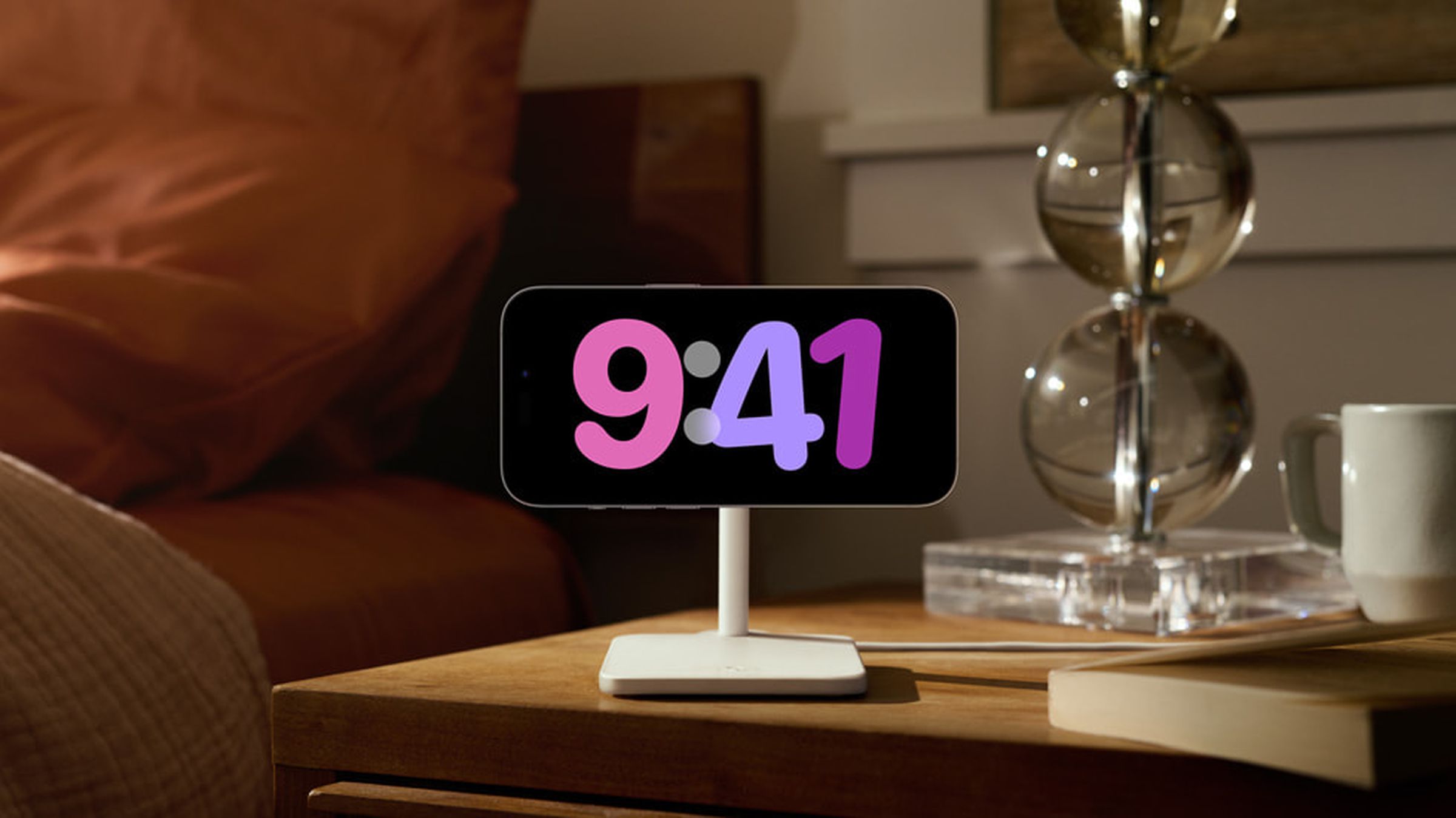 An iPhone sits on a stand in landscape orientation, with an artsy digital clock on the screen.