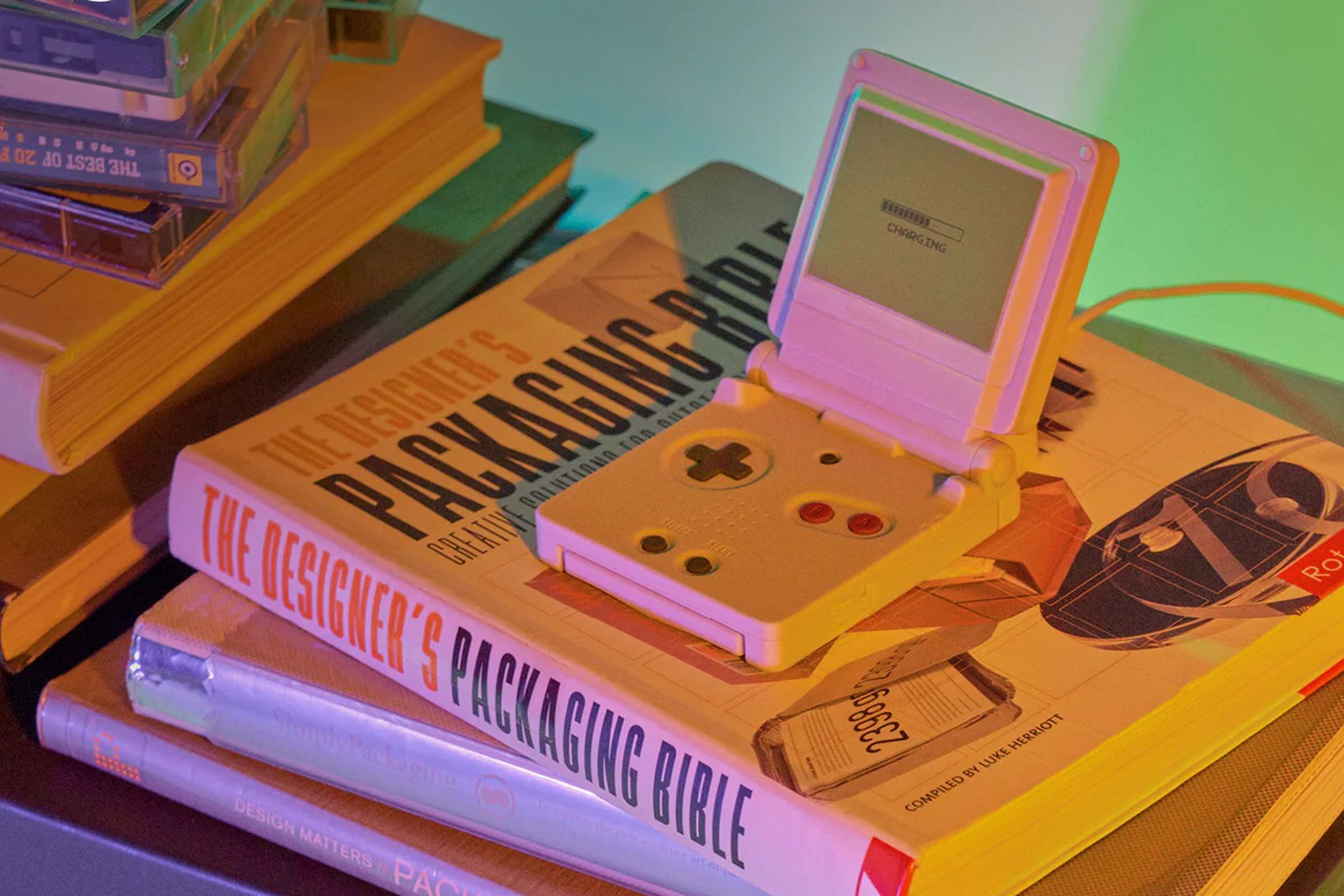 An image of a charger resembling a GameBoy SP on a stack of books.