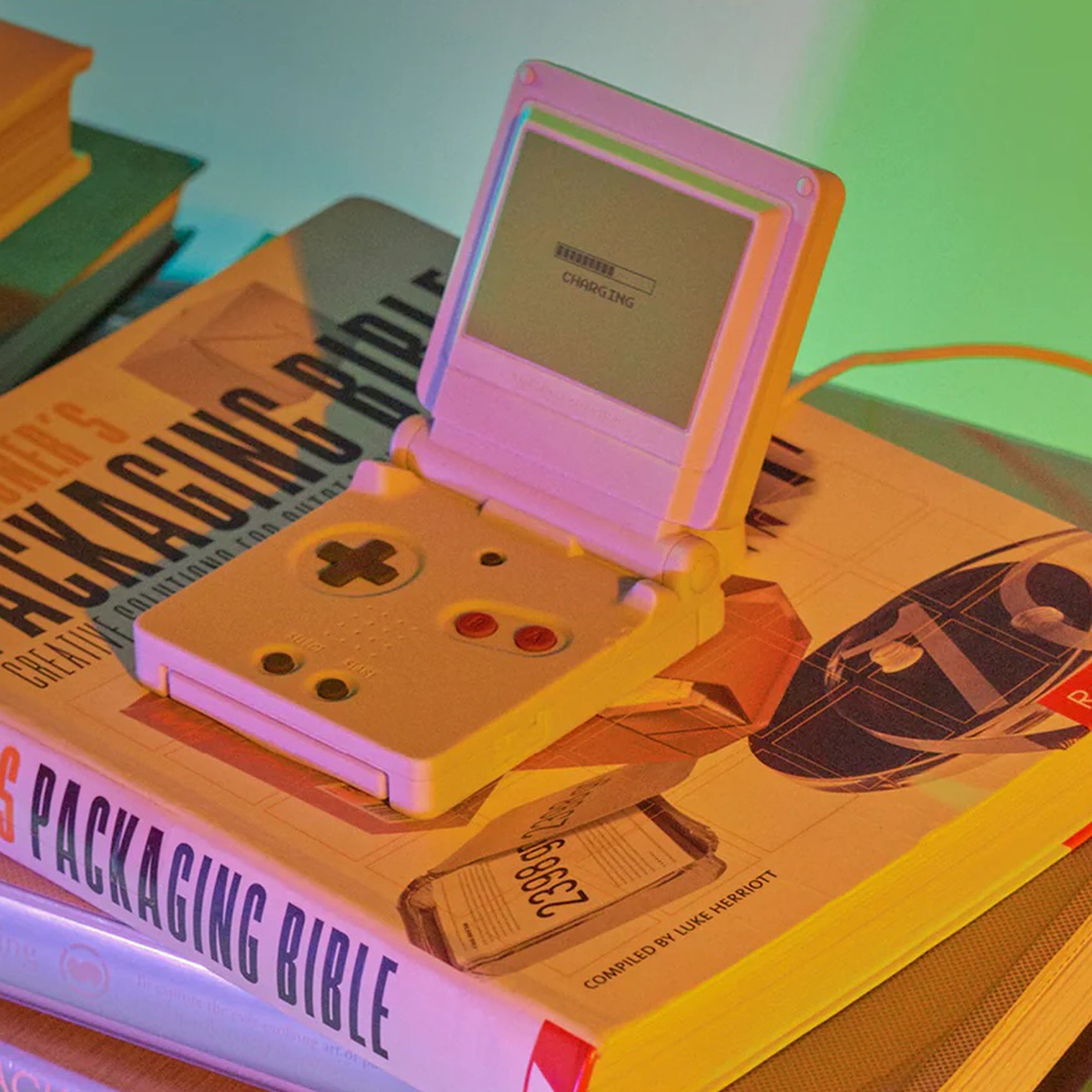 An image of a charger resembling a GameBoy SP on a stack of books.