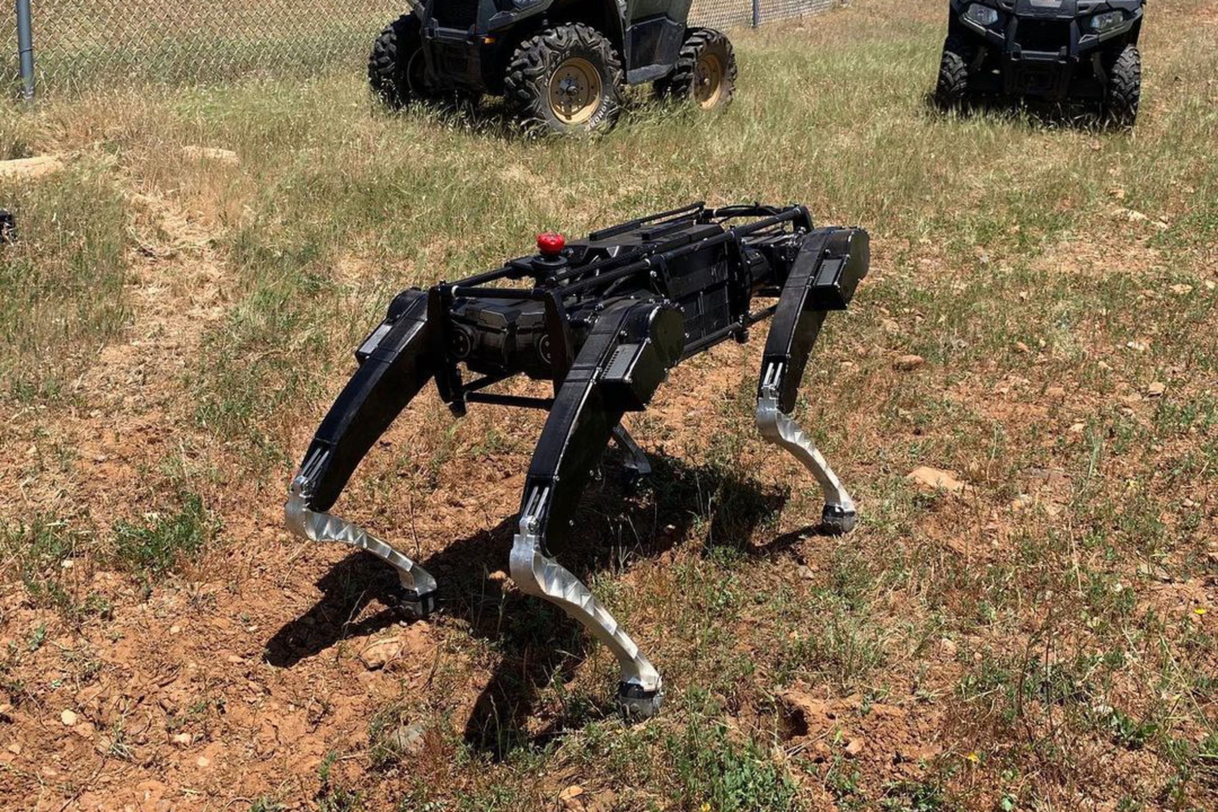 A Ghost Robotics quadruped posing alongside ATVs in the southwest US. 