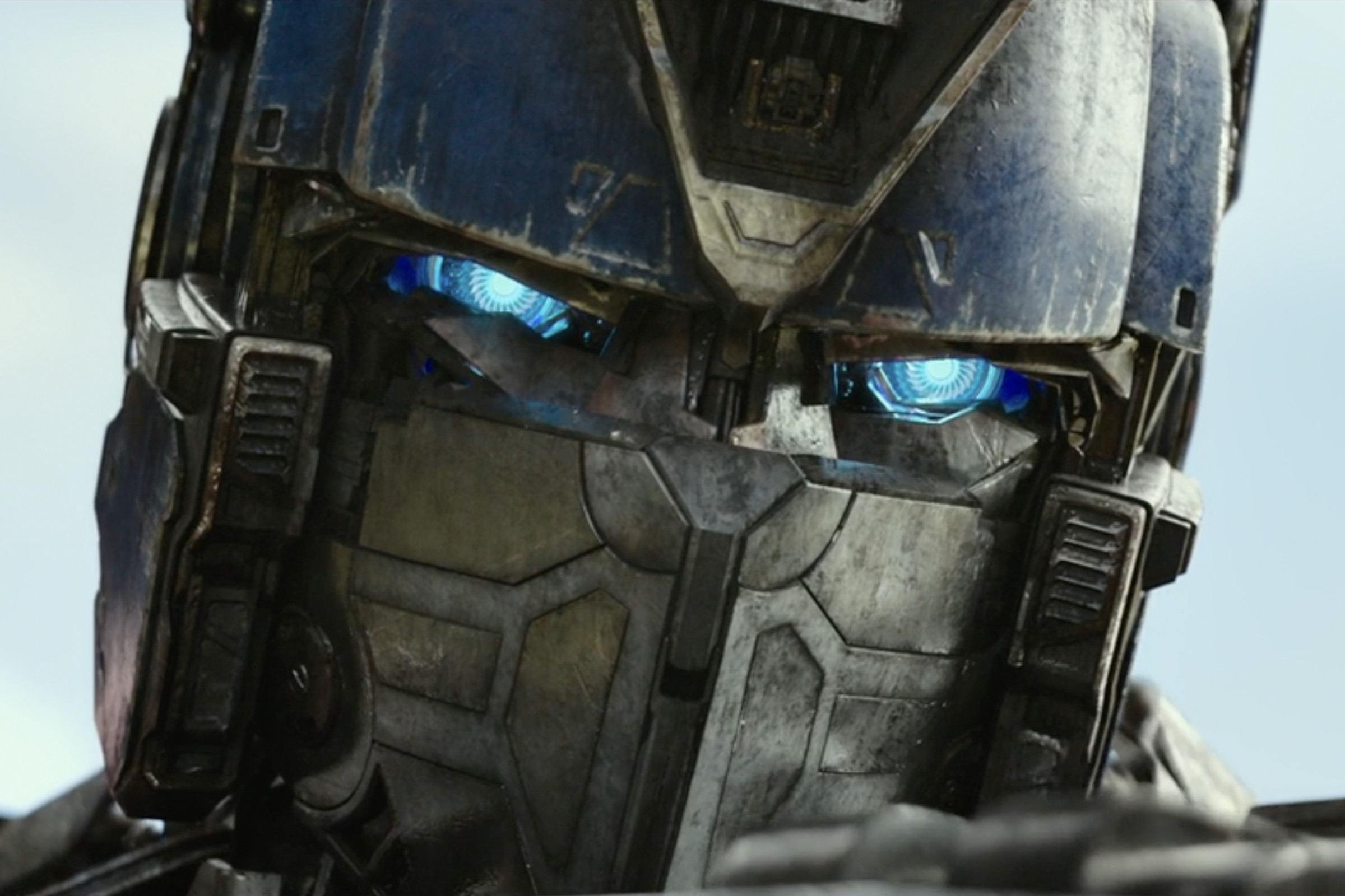 The head of a humanoid robot, the upper-half of which is blue, and the low half of which is gunmetal gray.