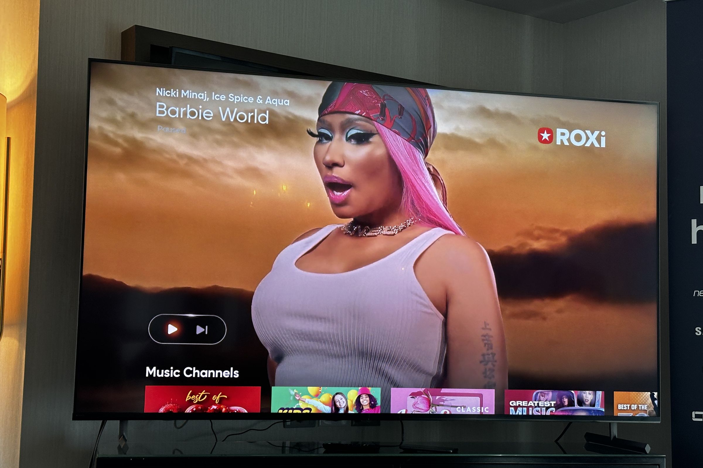An image of a Nicki Minaj on a TV screen. The screen is paused with a prominent UI, including a play and skip button.