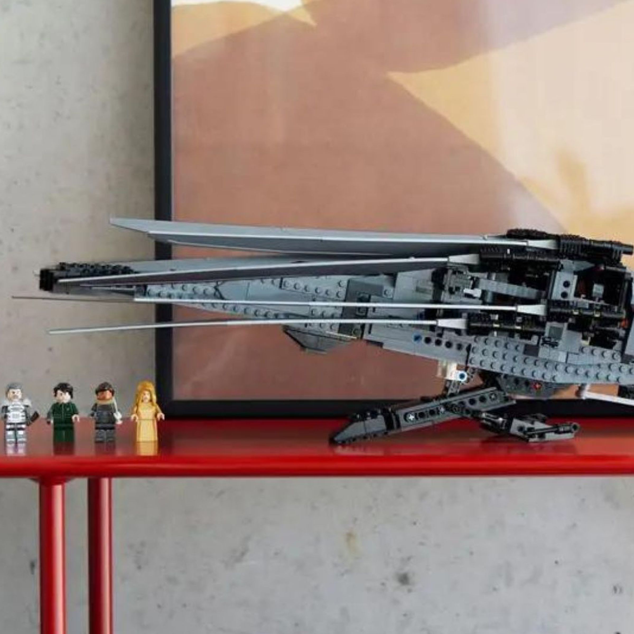 The Dune Atreides Royal Ornithopter Lego set on a shelf beside its eight character mini figurines.