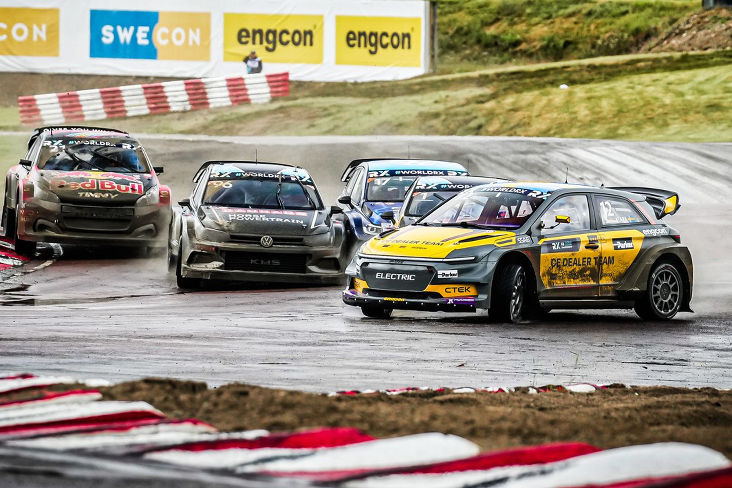 Several rally cars racing on a track, with the lede car mid-drift.