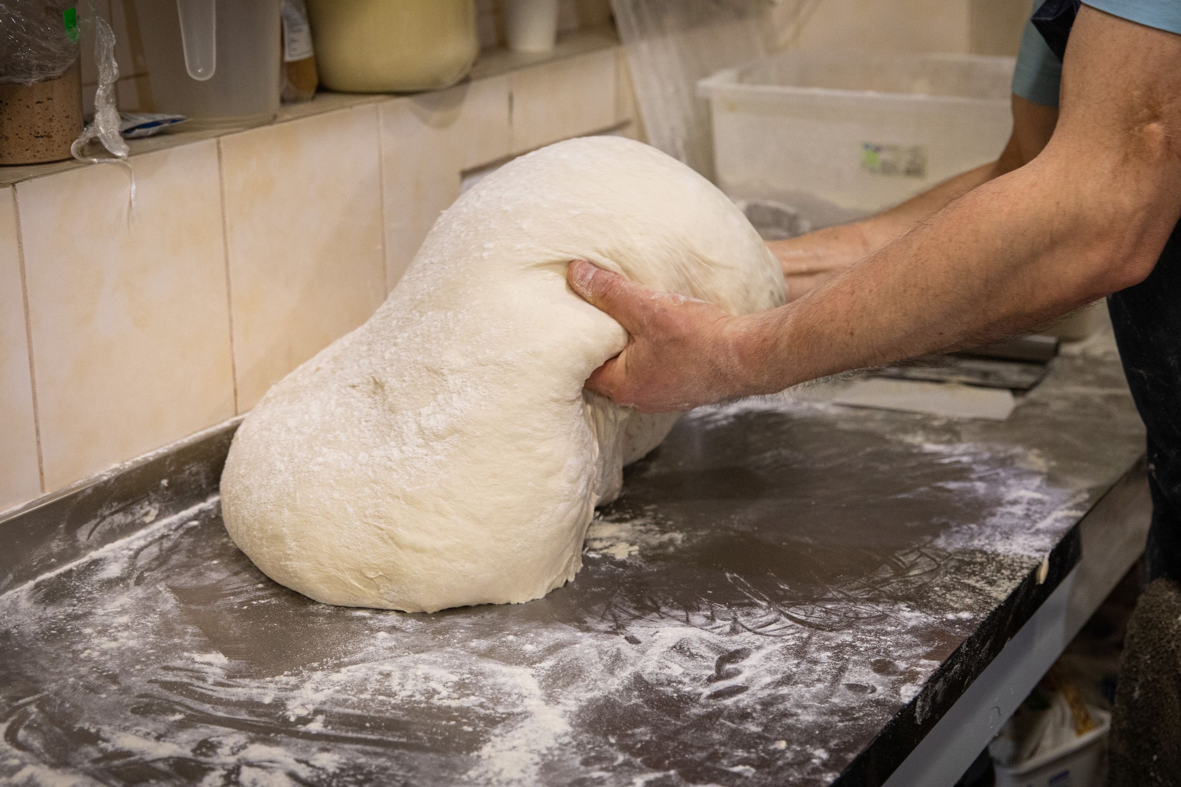 A bread baker makes dough for bread, as the bread will be...