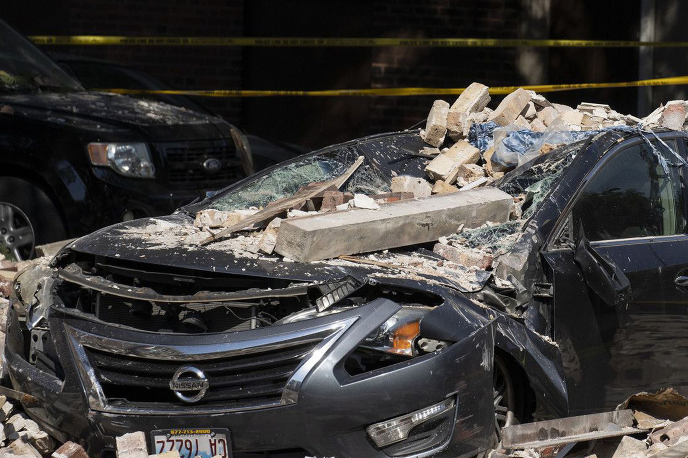 A Chicago firefighter checks a crushed car at the scene where a four-story building partially collapsed due to an explosion on Chicago’s West Side on Tuesday, Sept. 20, 2022.
