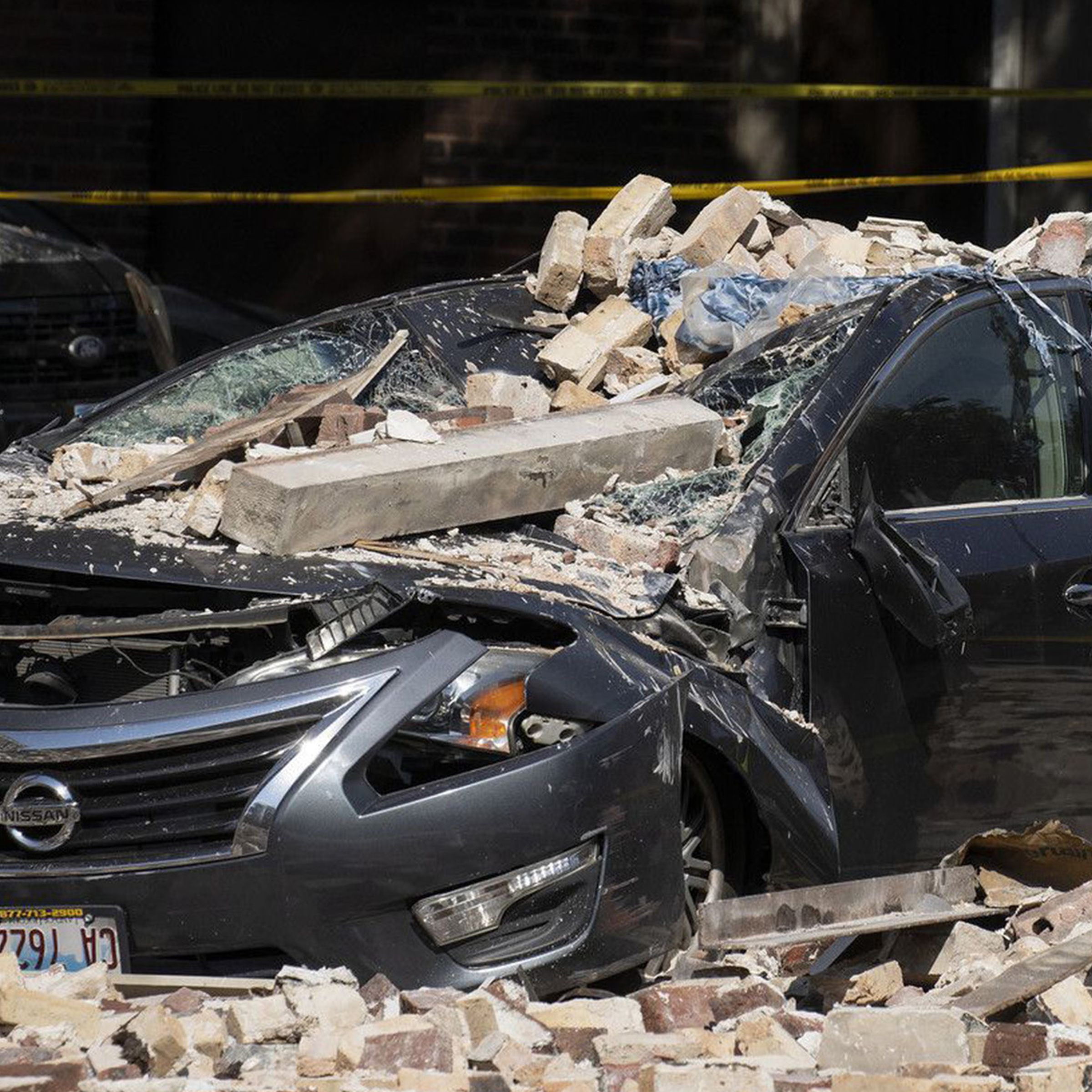 A Chicago firefighter checks a crushed car at the scene where a four-story building partially collapsed due to an explosion on Chicago’s West Side on Tuesday, Sept. 20, 2022.
