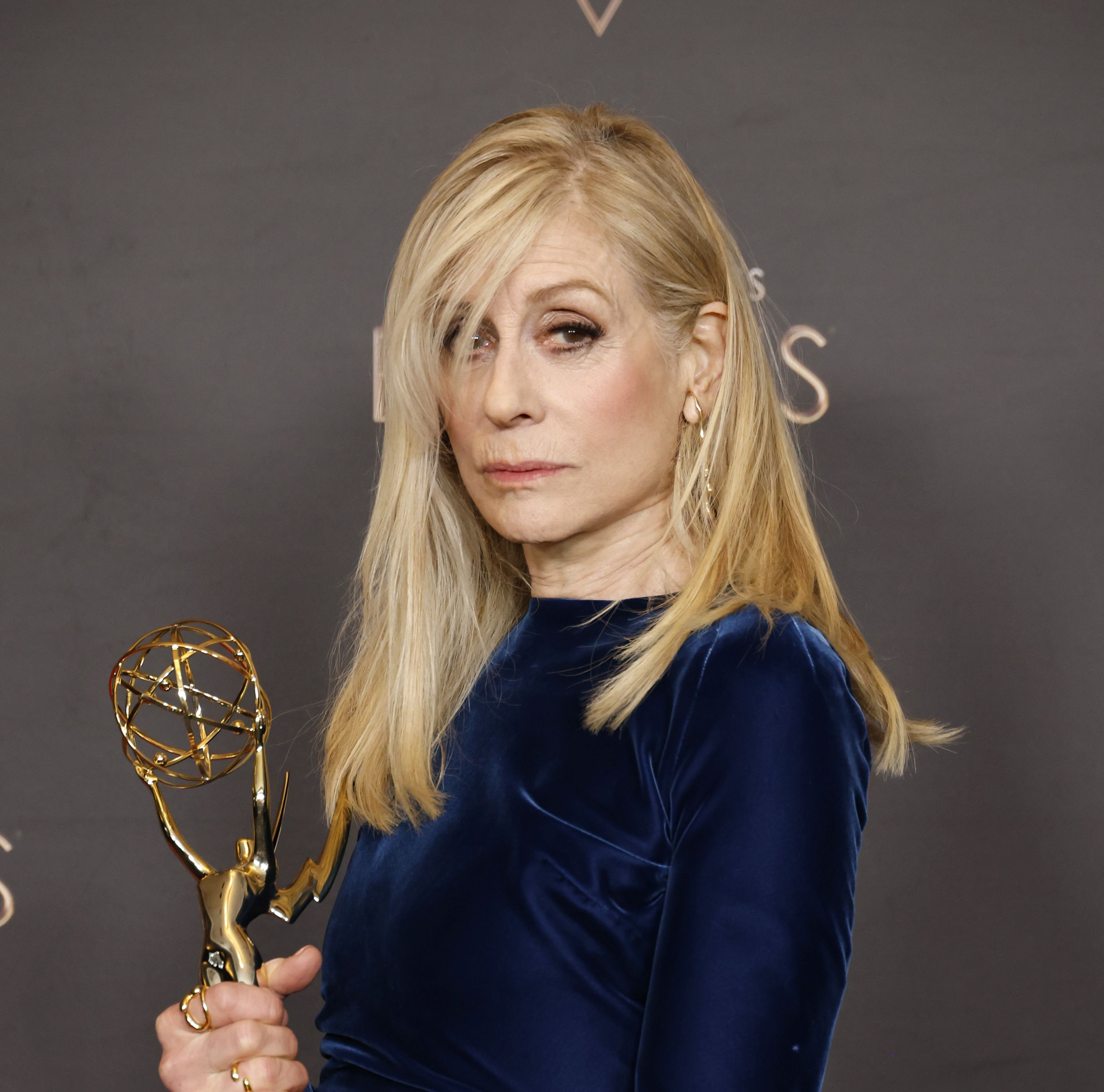 Judith Light in a blue gown holding her new Emmy.