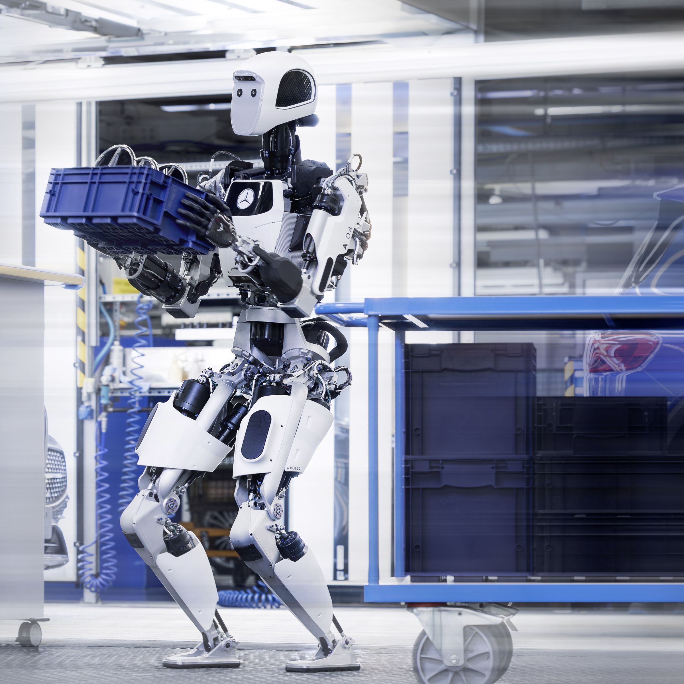 Apptronik’s Apollo robot carrying a blue crate in a Mercedes factory.