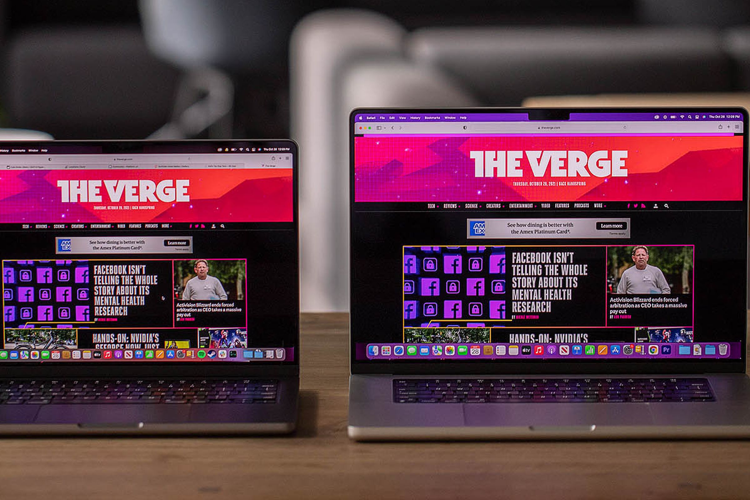 The MacBook Pro 14 and MacBook Pro 16 side-by-side on a table, both displaying The Verge homepage.