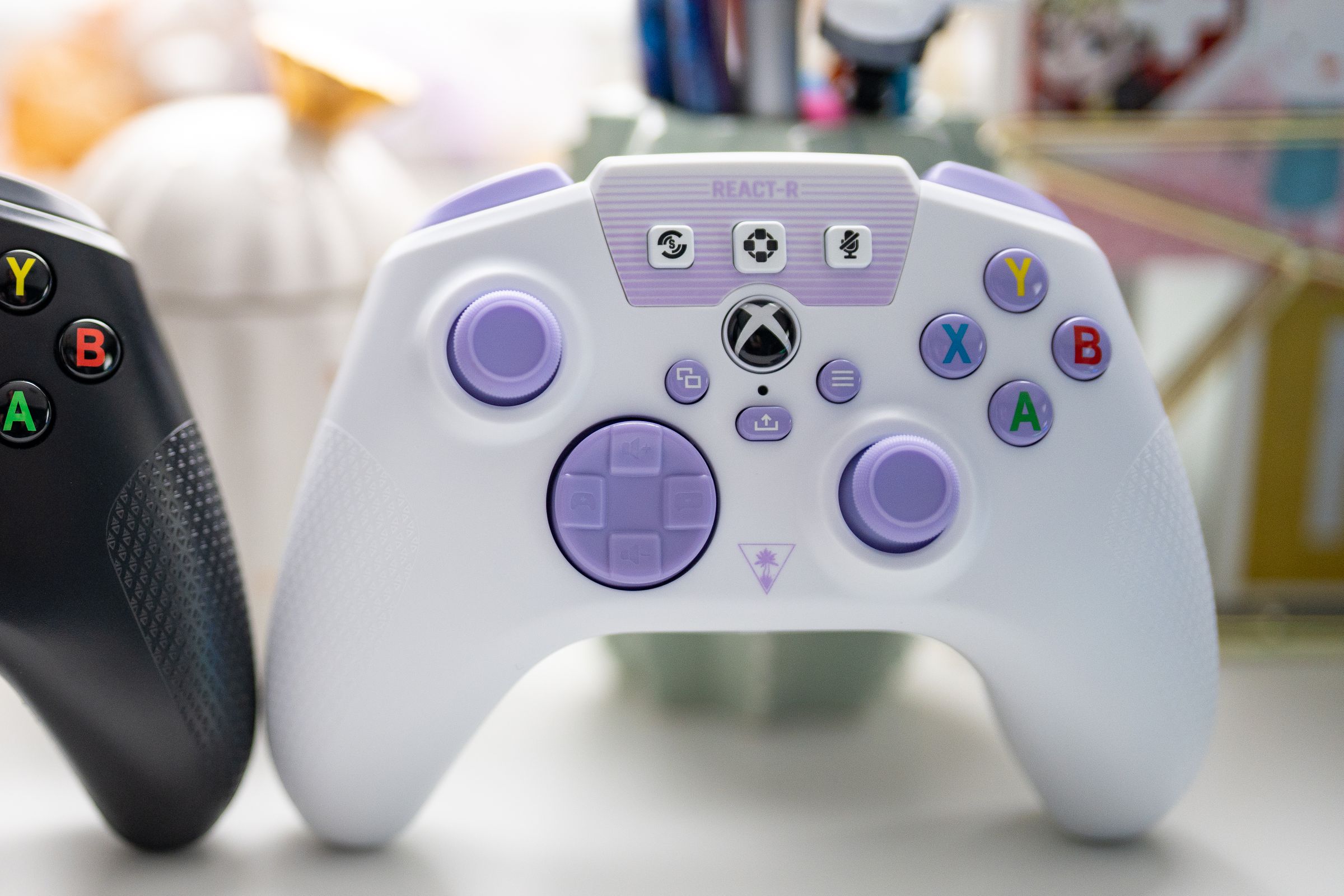 A side-by-side image of the Turtle Beach React-R controllers, black on the left and white / purple on the right.