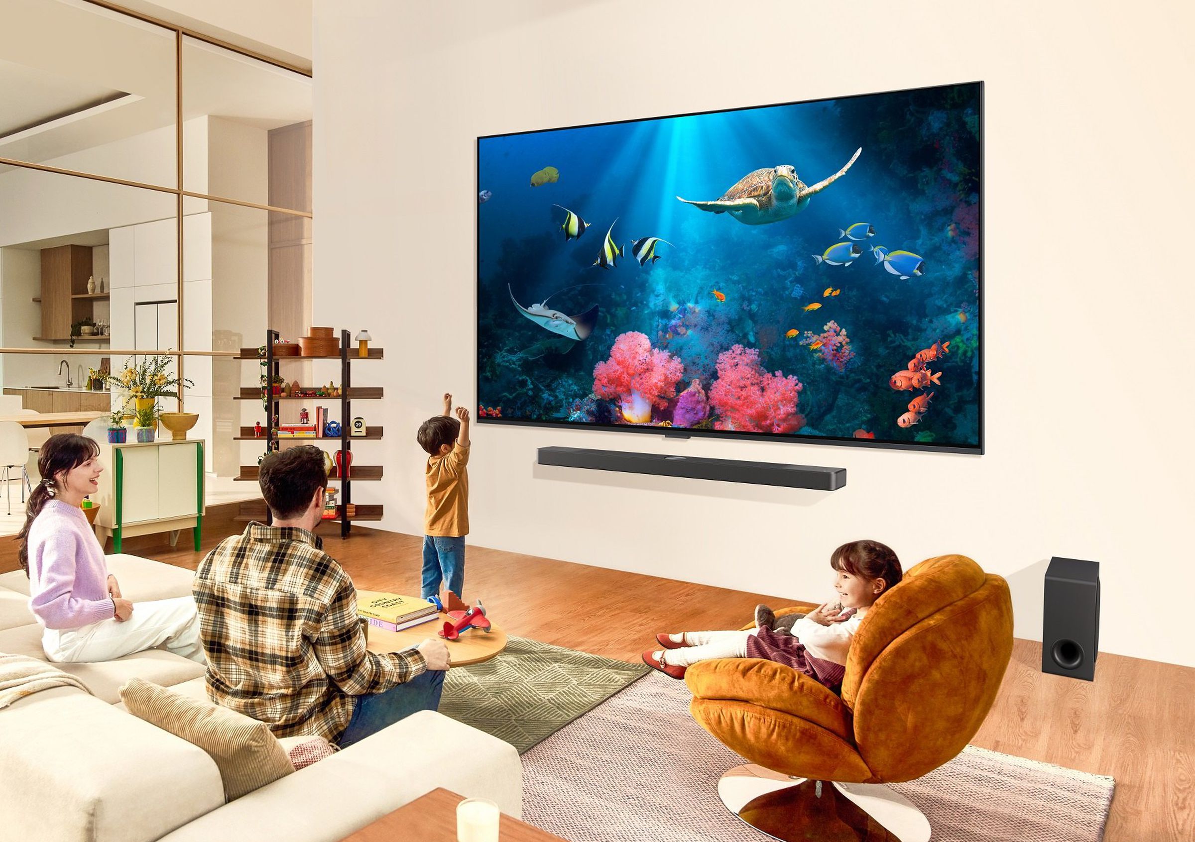 Promotional picture showing a simulated upscale living room area with parents and two children watching a massive wall-mounted LG television.