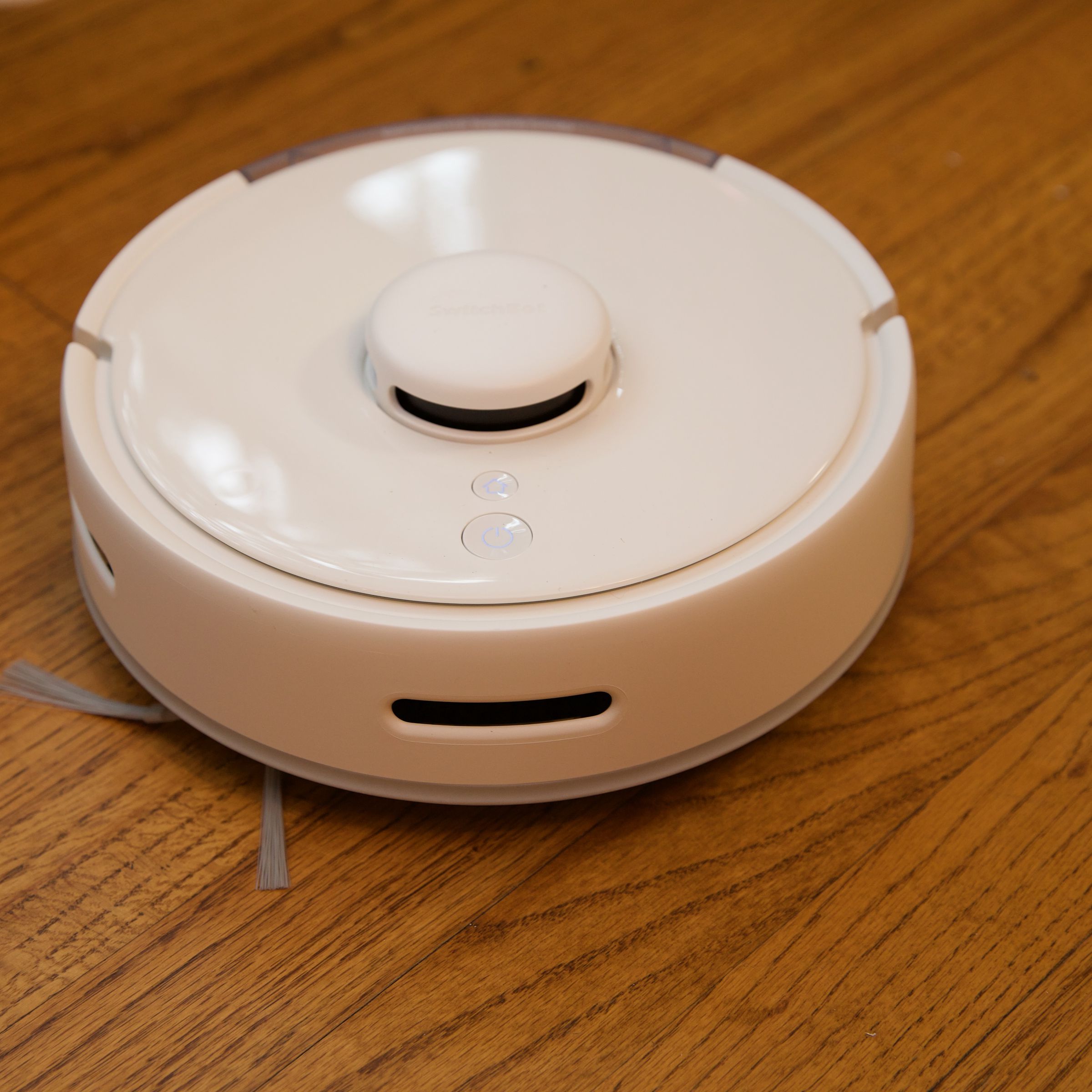 A white robot vacuum on a hardwood floor.