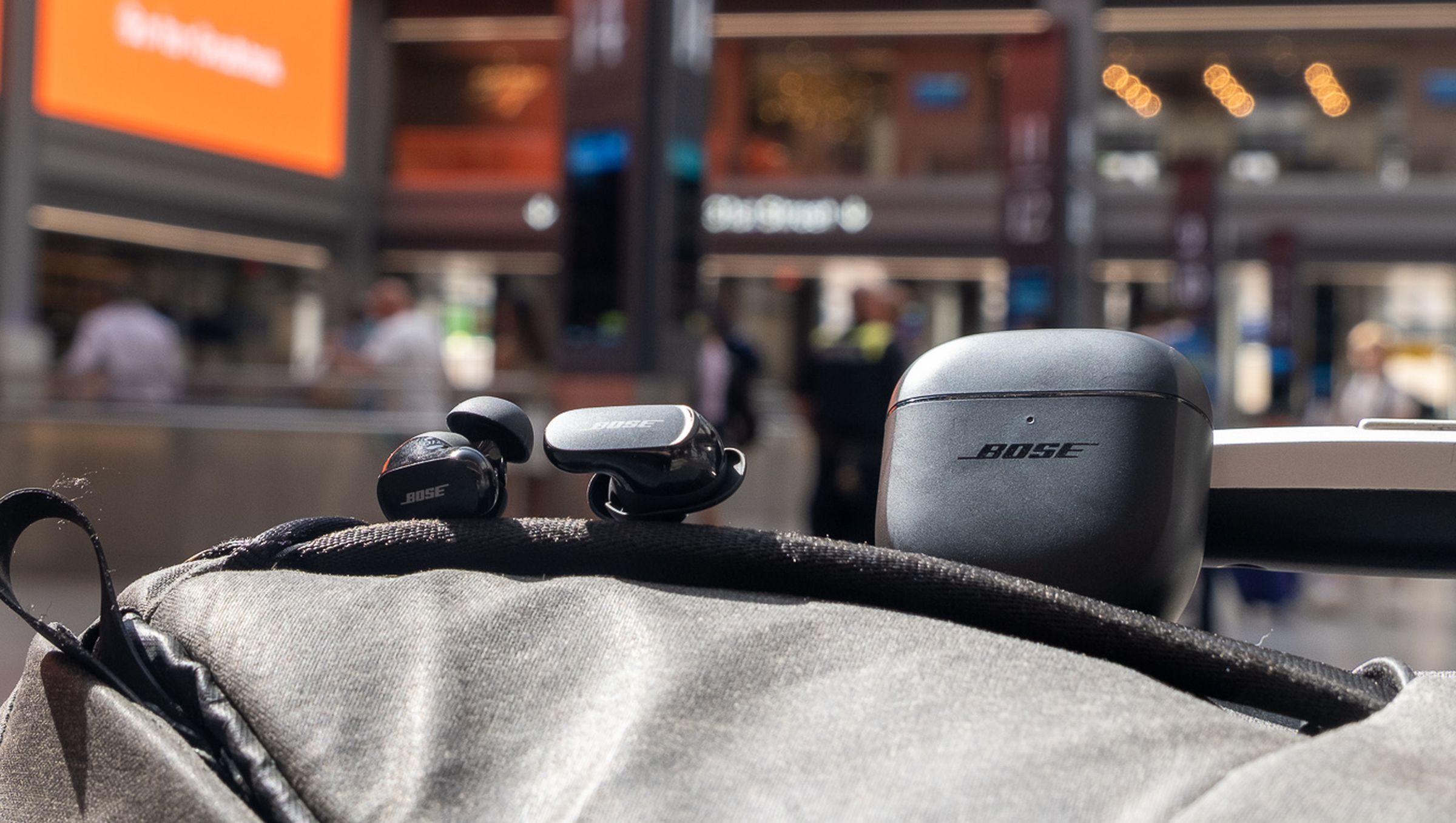 The Bose QC Earbuds II pictured on top of a backpack at Moynihan Train Hall in New York City.