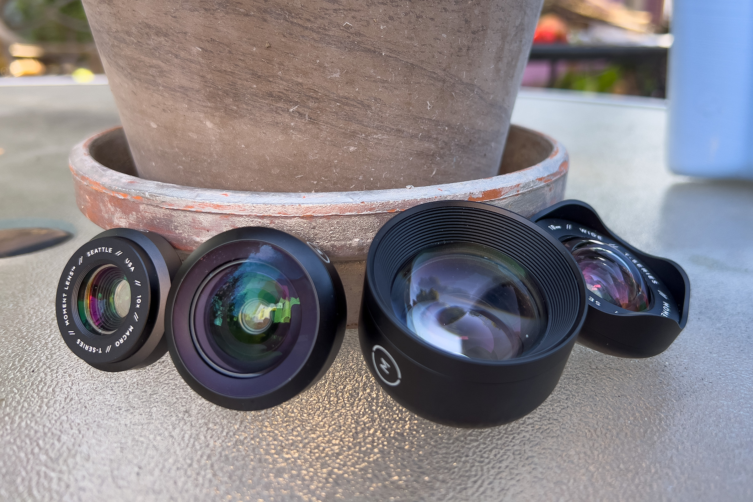 A picture of the Moment lenses leaning in a row against a flower pot.