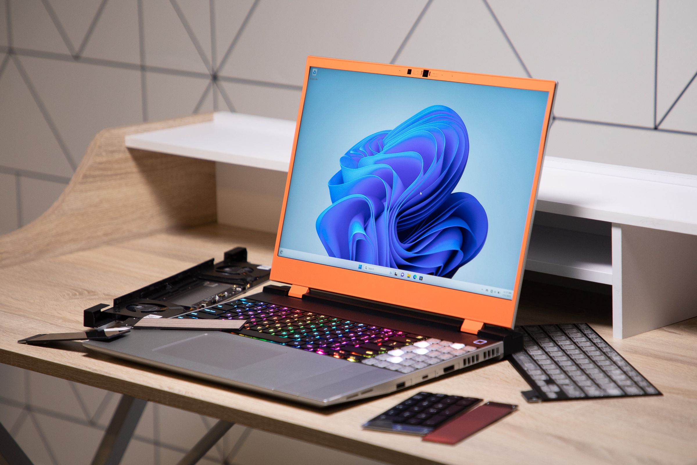 A laptop with an orange bezel and RGB keyboard and LED numpad and more bumpers surrounding it.