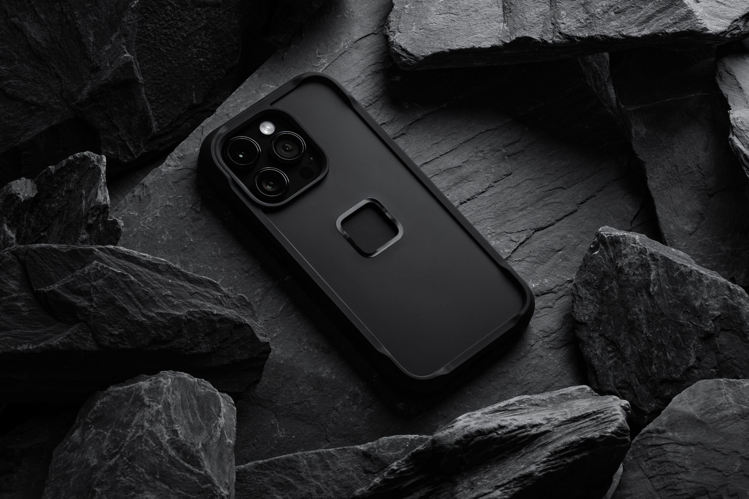 The Nomad x Peak Design rugged iPhone 14 Pro case placed against a pile of black slate.