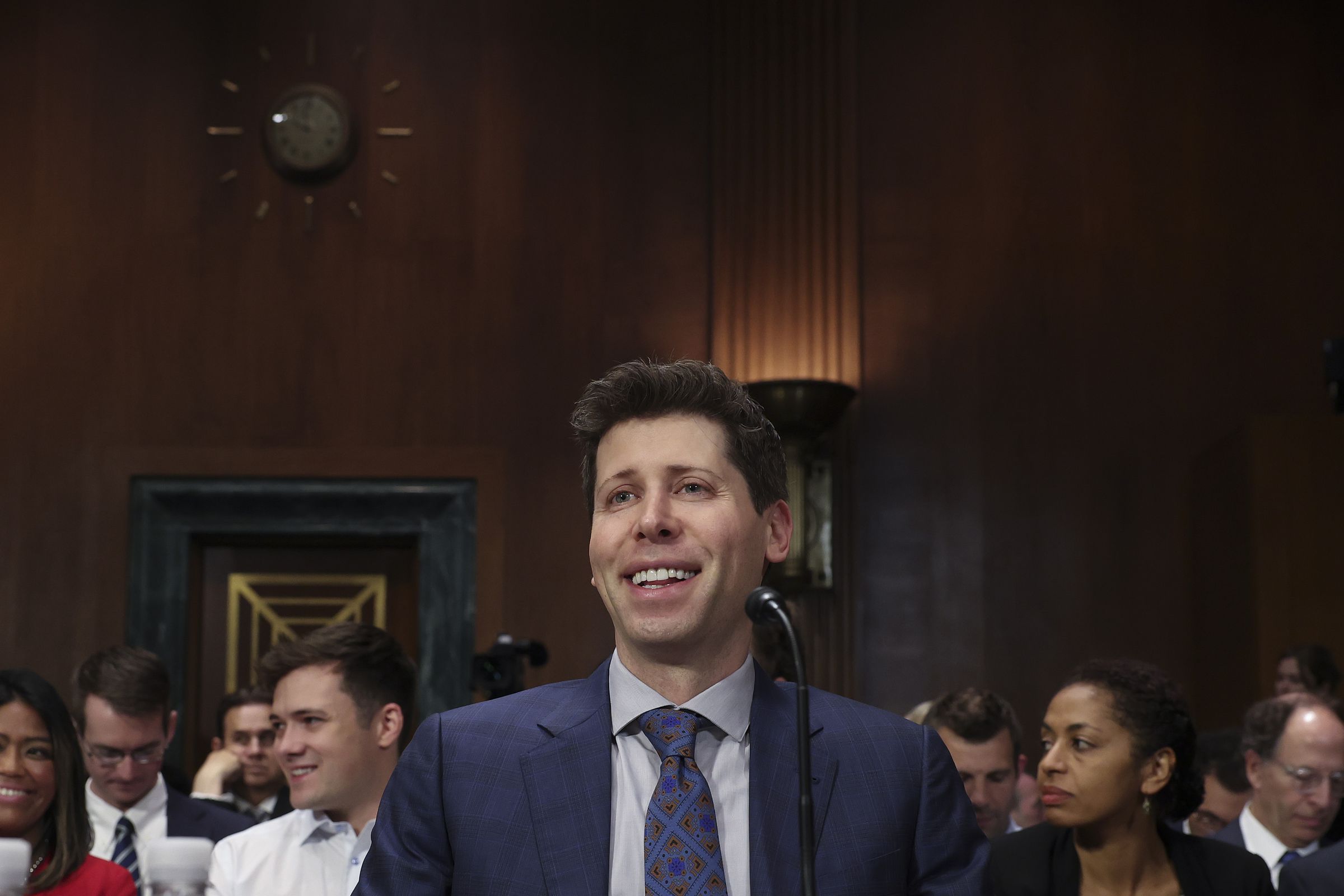 A photograph of Altman smiling broadly at the senate hearing.